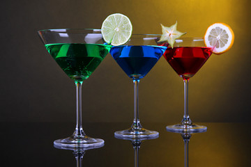 Alcoholic cocktails in martini glasses on dark yellow