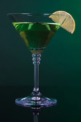Green cocktail with lime on dark green background