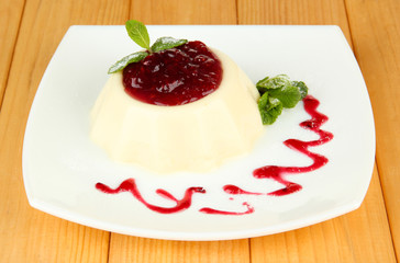 Panna Cotta with raspberry sauce, on wooden background