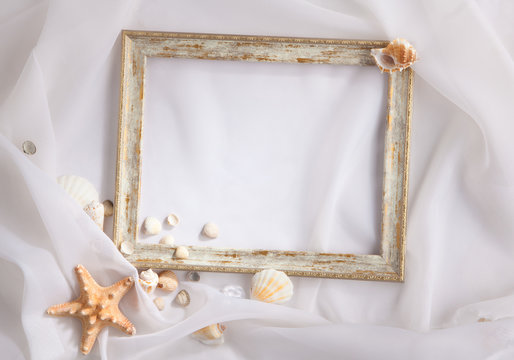 Shabby picture frame and shells, on white fabric