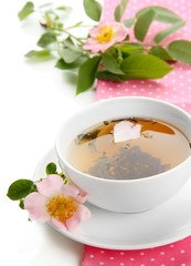 Cup of herbal tea with hip rose flowers, isolated on white
