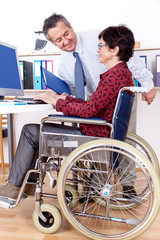 Man helps a wheelchair user in the office