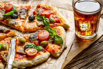 Freshly baked pizza served with a cold drink - obrazy, fototapety, plakaty