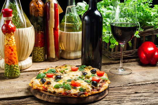 Baked pizza served with wine on the background of fresh vegetabl