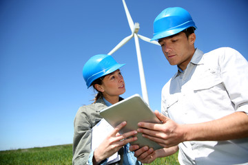 Engineers looking at wind turbine site with tablet