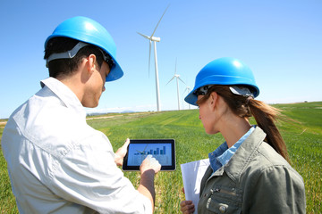 Engineers using tablet on wind turbine site