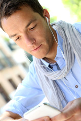 Handsome guy using smartphone and earphones