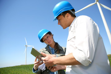 Engineers looking at wind turbine site with tablet