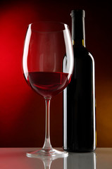 Glass of wine with bottle on bright red background