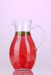 Cherry drink in pitcher on purple background.