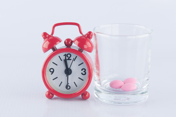 Red clock and pink tablet in  prescription glass