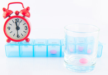 Red clock and pink tablet in prescription glass