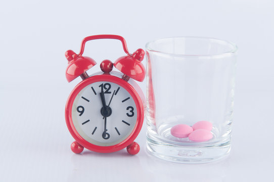 Red Clock And Pink Tablet In  Prescription Glass