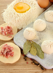 Raw dumplings, ingredients and dough, on wooden table