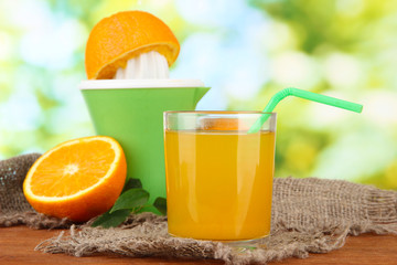 Citrus press, glass of juice and ripe oranges