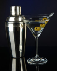 Martini glass with olives on dark blue background