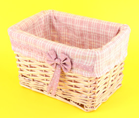 Wicket basket with pink fabric and bow, on color background