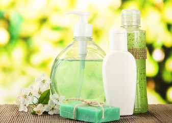 Cosmetics bottles and natural handmade soap on green background