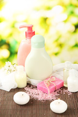 Cosmetics bottles and natural handmade soap on green background