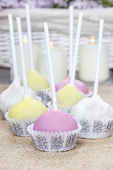 Colorful cake pops on hessian, birthday party. Candles in the ba
