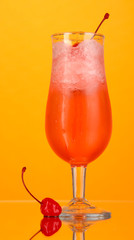 Cherry cocktail with ice on orange background