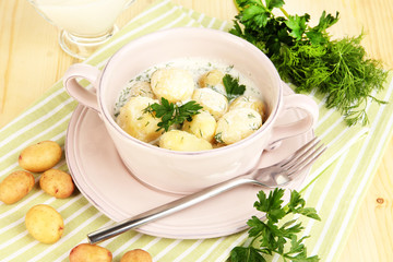 Tender young potatoes with sour cream and herbs in pan