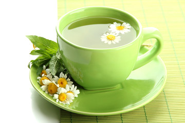 Cup of herbal tea with wild camomiles and mint, isolated