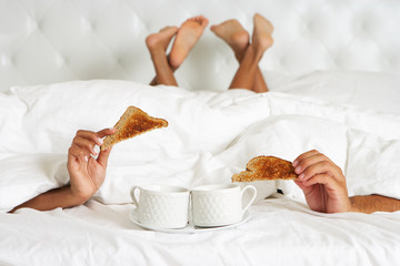 Couple Hiding Under Duvet Enjoying Breakfast In Bed - obrazy, fototapety, plakaty