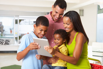 Family Using Digital Tablet In Kitchen Together