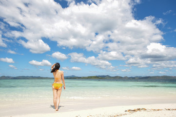 Fototapeta na wymiar Back portrait of young bikini girl looks up on beach