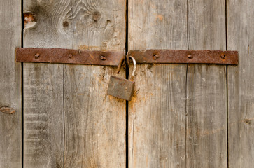 Old rusty padlock on a wooden door
