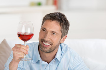 lächelnder mann schaut auf ein glas rotwein