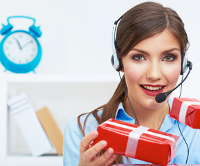 Smiling operator seat at table with red gift box. Happy busines