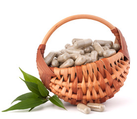 Herbal drug capsules in wicker basket. Alternative medicine conc