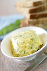 Butter mit Kräutern und Brot im Hintergrund