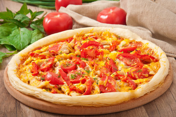 Appetizing pizza with chicken, tomatoes, peppers and cheese