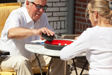 Senior couple playing dice game outdoor in garden. Yahtzee.