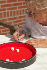 Senior woman writing his score on paper outdoor in garden. Playi
