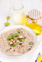 Useful oatmeal in bowl with fruit on wooden table close-up
