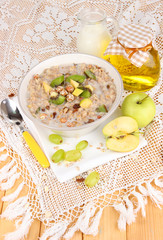 Useful oatmeal in bowl with fruit on wooden table close-up