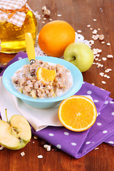 Useful oatmeal in bowl with fruit on wooden table close-up