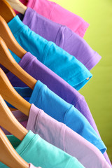 Lots of T-shirts on hangers on green background