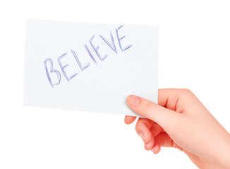 Believe word on piece paper in hand isolated on white