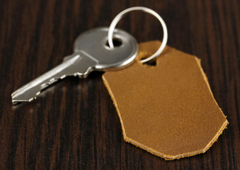 Key with leather trinket on wooden background