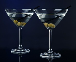 Martini glasses with olives on dark blue background