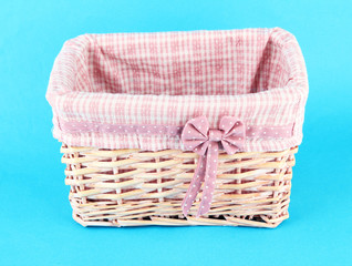 Wicket basket with pink fabric and bow, on color background