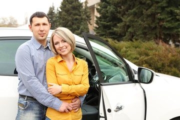 Portrait of happy beautiful couple standing near the car