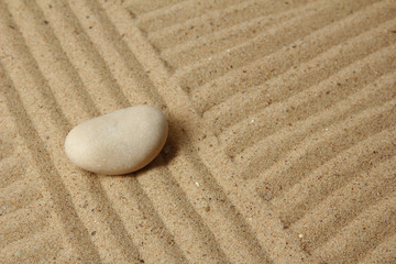 Zen garden with raked sand and round stone close up