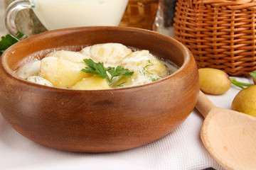 Tender young potatoes with sour cream and herbs in wooden bowl