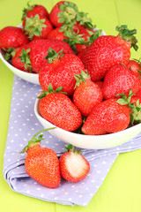 Fresh strawberry in bowl on green wooden background